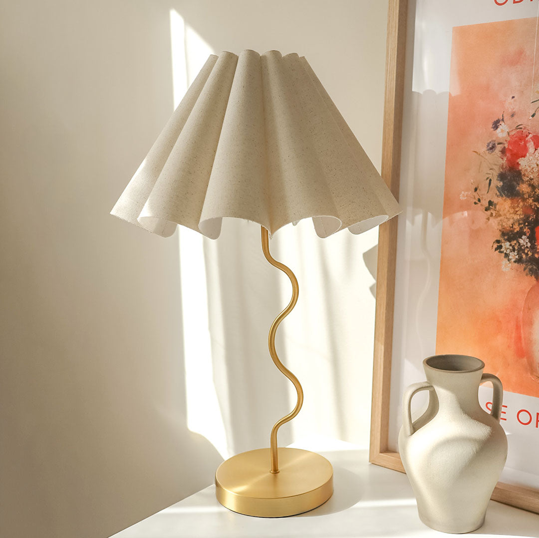 Cora Table Lamp – three-quarter view of the cream linen fluted shade on a brass squiggly base by Paola And Joy
